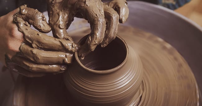 Hands shaping clay on a spinning wheel, symbolizing self-transformation and Guru Nanak’s teaching of Oneness in Gurbani.